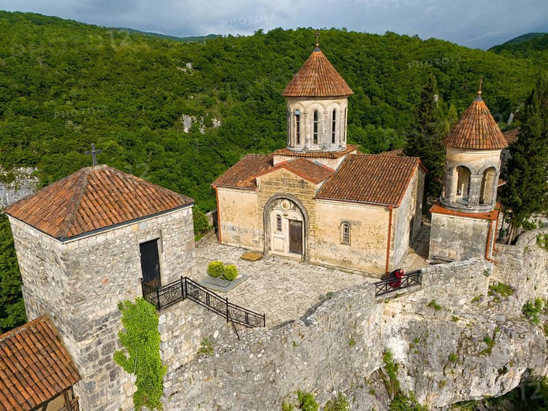 Historic church with tiled roofs on a hill surrounded by dense forest, aerial view, Motsameta Monastery, near Kutaisi, Imereti region, Georgia