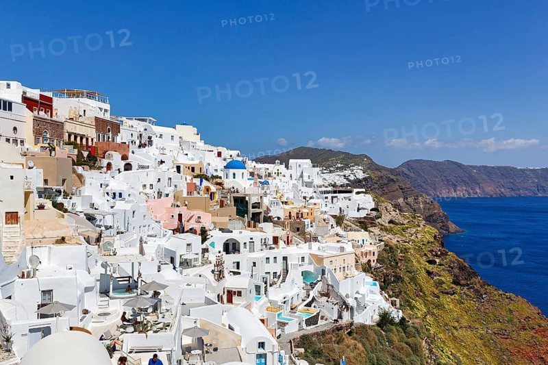 White and colourfully painted holiday homes, orthodox church with blue dome on the edge of the caldera, cliffs, Oia, Thira, Santorini, Cyclades, Greece