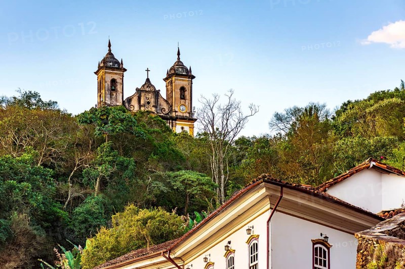 Historic buildings and a baroque church amidst the vegetation of the hills of the city of Ouro Preto, Ouro Preto, Minas Gerais, Brazil