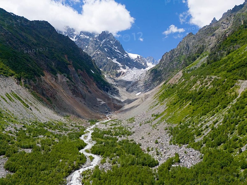 Imposing mountain scenery with glacier in the valley, surrounded by green forests and a meandering river under a clear sky, aerial view, Chalaadi glacier, Mestia, Svaneti, Caucasus, Georgia