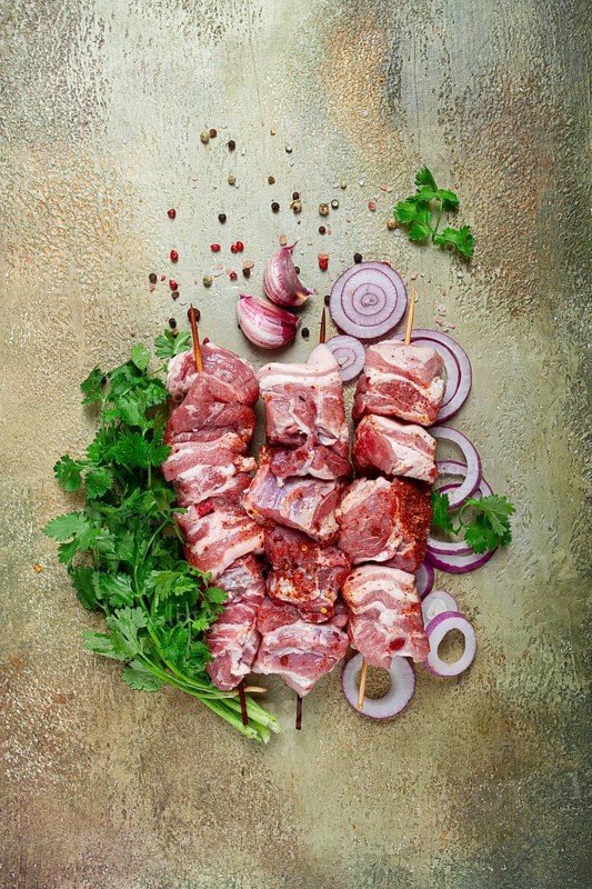 Raw pork meat, on wooden skewers, pickled kebab, with spices and herbs, on the table, top view, no people