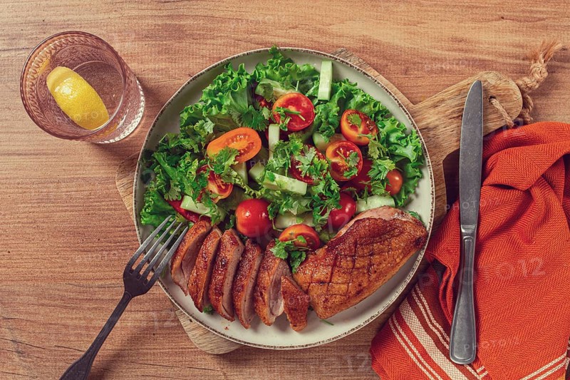Delicious grilled duck breast served with fresh garden salad and cherry tomatoes at a rustic dining table