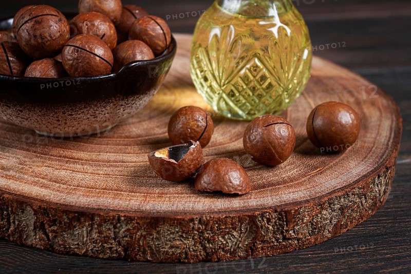 Bottle of macadamia oil, on a wooden board, with macadamia nuts, wooden background, selective focus, no people