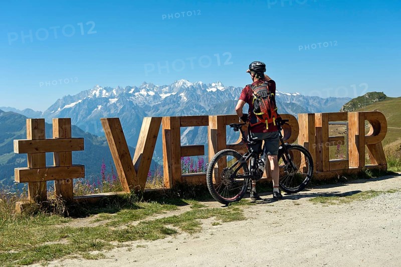 Mountain biker looks from the photo spot 'Verbier' on the Col de la Croix de Cœur pass to the mountain range of the Alps, Verbier, Valais, Switzerland
