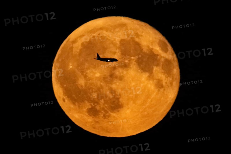 The silhouette of an aeroplane stands out against the full moon, Frankfurt am Main, Hesse, Germany