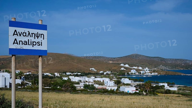 A town sign in front of a coastal settlement with whitewashed houses and blue sky, Analipsi, Maltezana, Astypalea, Astipalea, Astipaleia, Dodecanese, Greek Islands, Greece