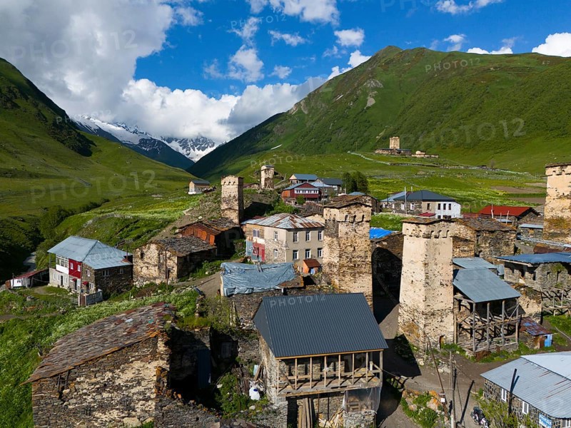 Medieval village with stone towers in a green valley surrounded by mountains and cloudy sky, aerial view, defence towers, Ushguli, Ushguli, Shibiani district, Zhibiani, Upper Svaneti, Svaneti, Georgia