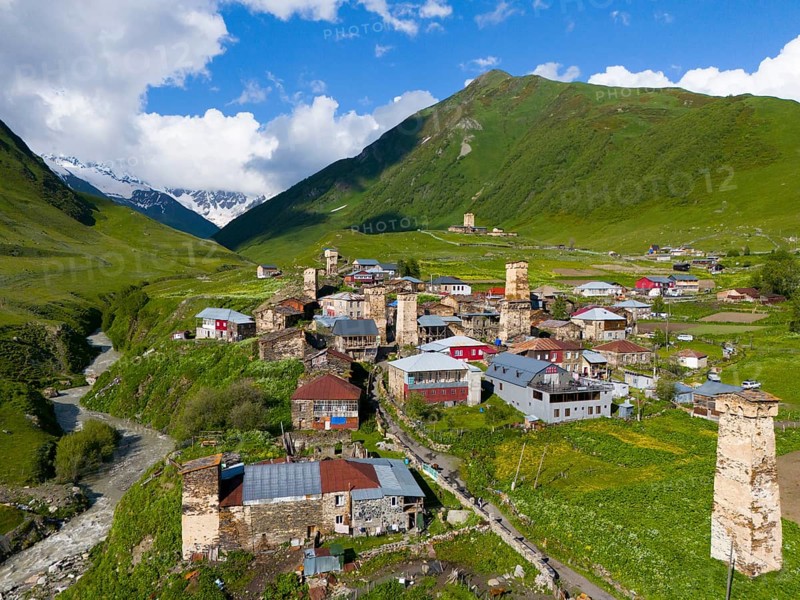 A picturesque mountain village with historic towers and green hills under a blue sky, aerial view, defence towers, Ushguli, Ushguli, Shibiani district, Zhibiani, Enguri River, Inguri, Upper Svaneti, Svaneti, Georgia