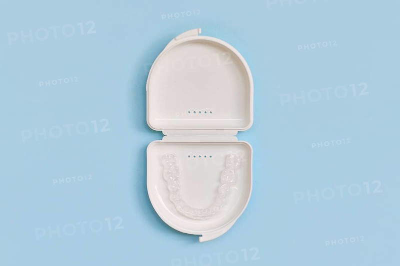 Customized transparent dental teeth bite guard clear aligners for lower jaw in white case on blue background