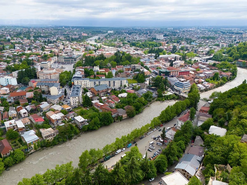 Urban panoramic view with river surrounded by dense residential areas and green trees under a cloudy sky, aerial view, Kutaisi, Kutaisi, Imereti region, Georgia, Asia