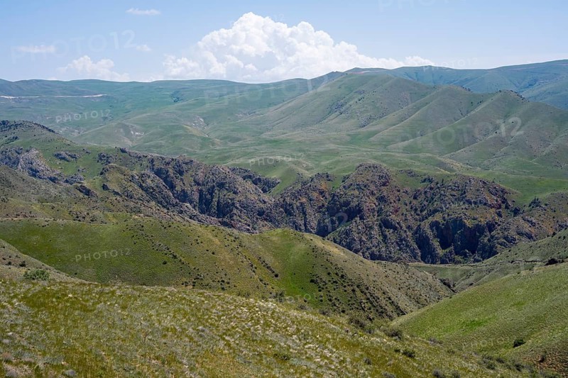 Green hills with clouds in the sky and a gorge depicting a peaceful landscape, view of the Azerbaijani enclave of Nakhchivan, Nakhichevan, M2, Armenia