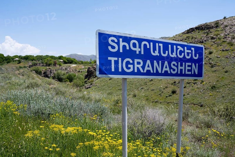 Road sign of Tigranashen in front of a hilly landscape with wild flowers, K?rk, Karki or Tigranashen is a village belonging to Azerbaijan under international law and surrounded by Armenian territory, occupied by Armenia and administered by the province of Ararat, Azerbaijani exclave, M2 leads through it, Azerbaijan