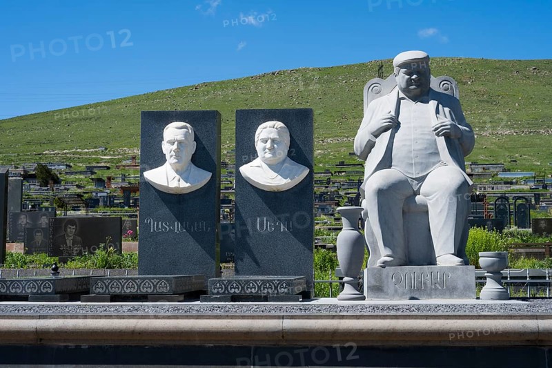 Stone busts and figure on a cemetery in front of a green hill and blue sky, Gyumri, Alexandropol, Leninakan, Shirak Province, Armenia