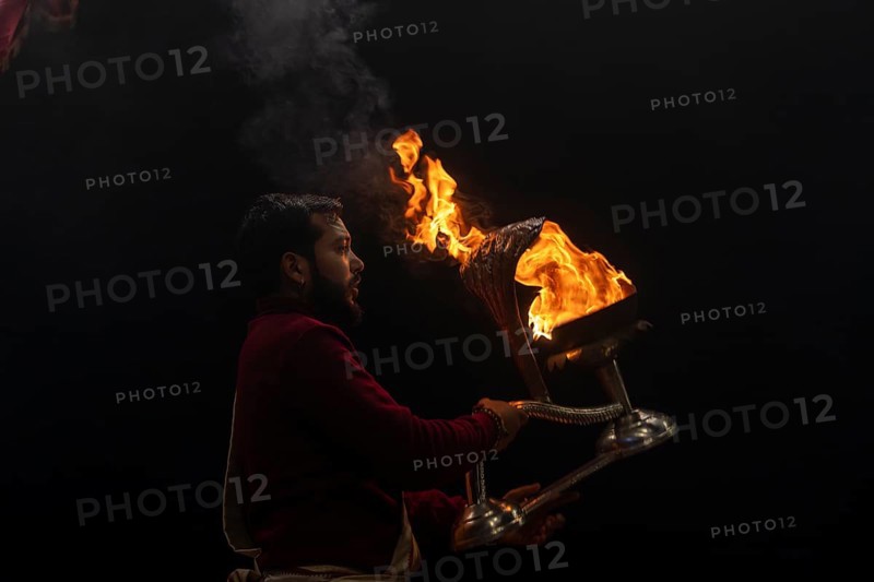 Hindu priest performing the Aarti ritual, holding a burning oil lamp, at the Ganges, Bangali Tola, Varanasi, Uttar Pradesh, India