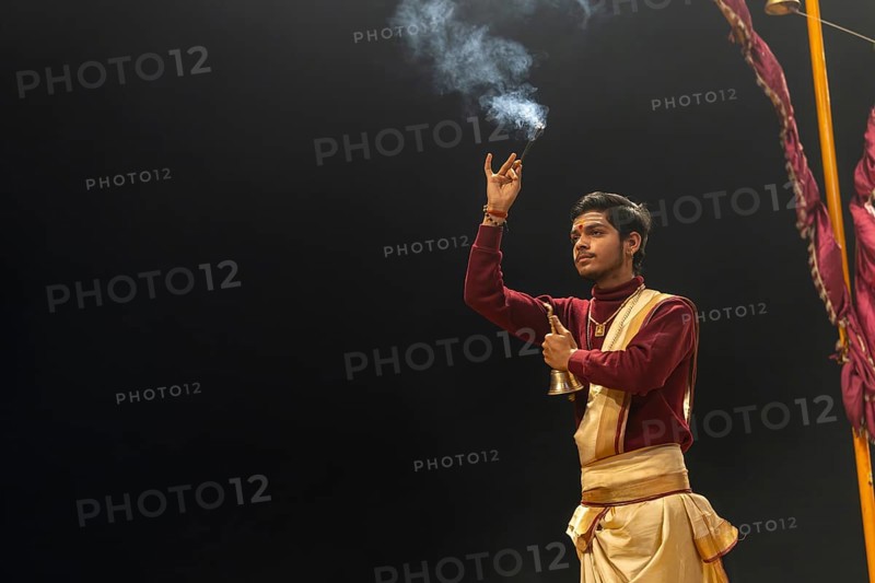 Hindu priest performing the Aarti ritual, at the Ganges, holding incense sticks and a bell, Bangali Tola, Varanasi, Uttar Pradesh, India