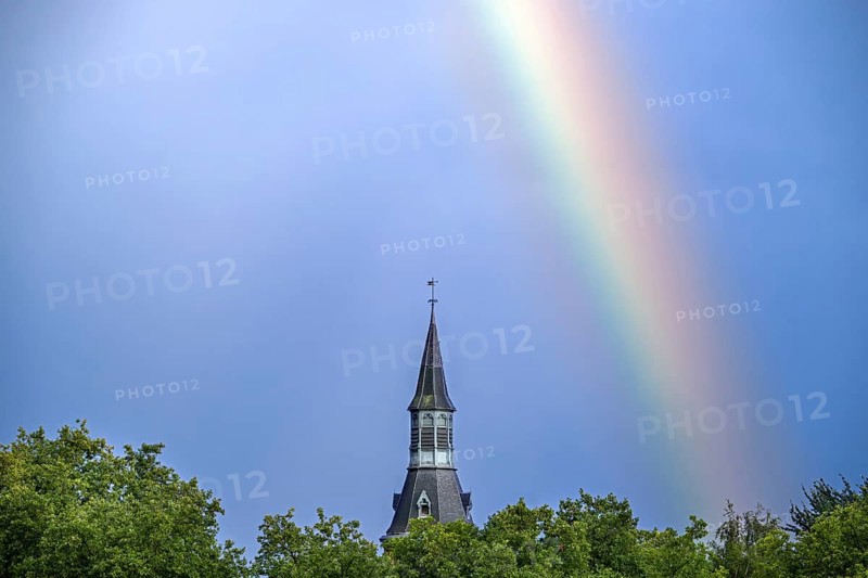 Colourful rainbow over trees and castle tower after downpour during thunderstorm in summer