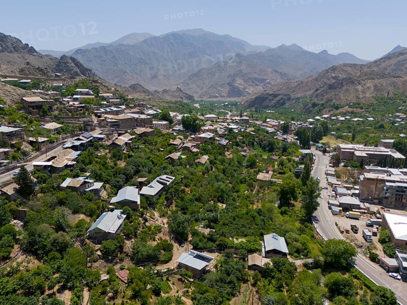 Panoramic view of a village along a road amidst green hills and mountains, aerial view, Meghri, Syunik province, mountains in the background are located in Iran, Armenia, Asia