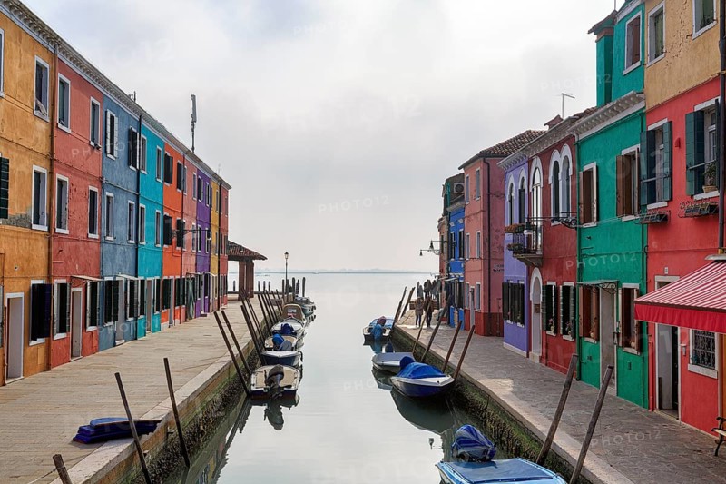 Boats on the canal, typical street scene in winter, colourful facades, various fishermen's houses in Burano, island in the lagoon of Venice, Italy