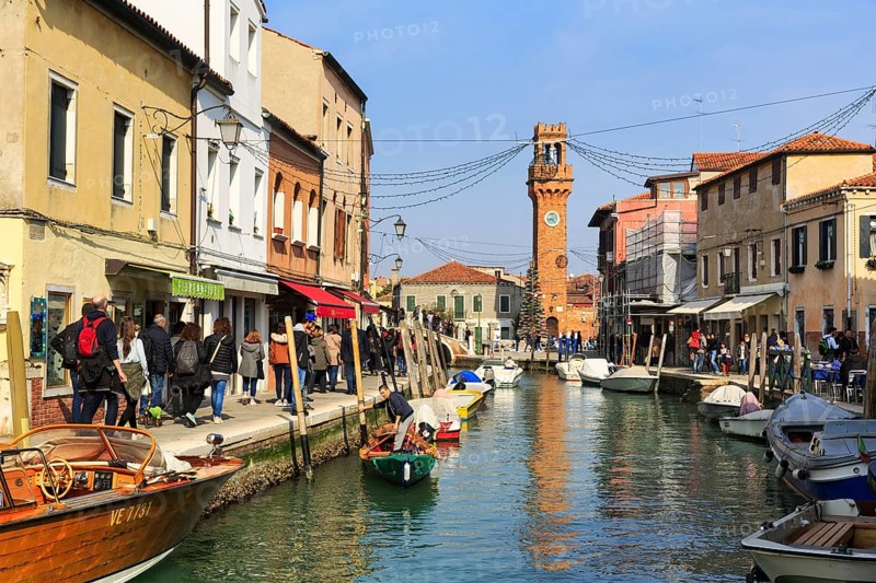 Strollers along the canal, typical street scene in winter, campanile of the church of San Giacomo, Murano, island in the lagoon of Venice, Italy
