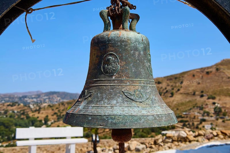 Antique metal bell in rural setting with background landscape and blue sky, Panagia tou Paleokastro, Church of the Old Fortress, Chapel, Panagia Kasteli, Lepides, Leros, Dodecanese, Greek Islands, Greece