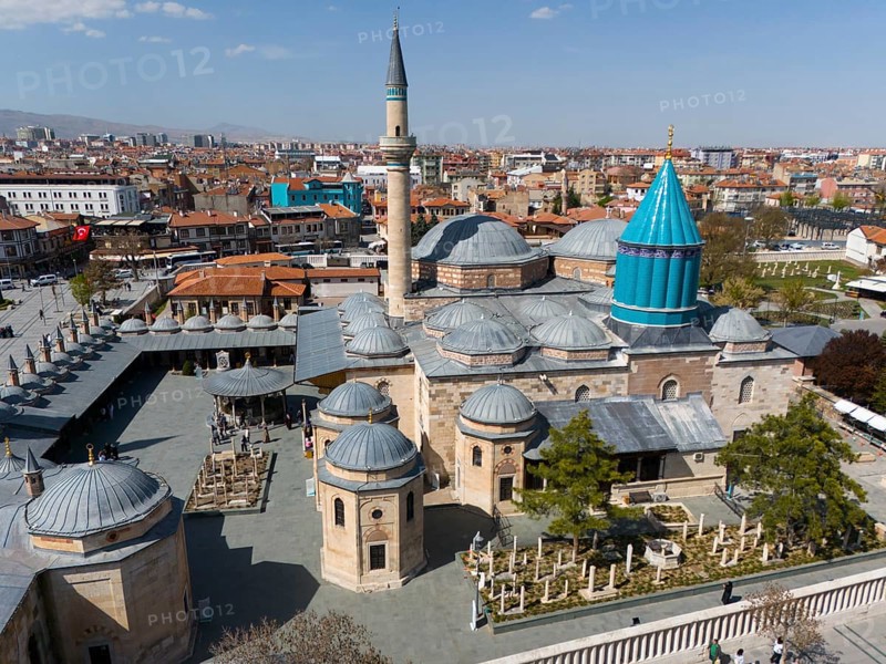 Historic mosque with minaret and domes in the middle of a cityscape under a blue sky, aerial view, Mevlânâ Museum, landmark, Mausoleum of Mevlânâ Jalal ad-Din Rumi, Konya, Central Anatolia, Turkey