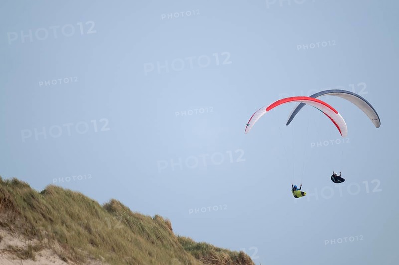 Two paragliders or paragliders in front of a blue sky over a dune landscape, near Hvide Sande, North Sea, Denmark