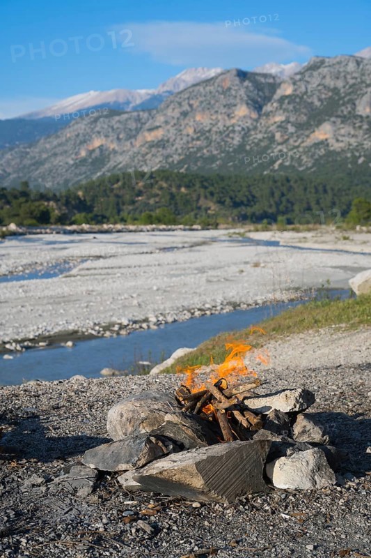 A campfire in a rocky landscape with mountains and a riverbed in the background, Dargaz River near Saklikent, Saklikent, Antalya Province, Turkey