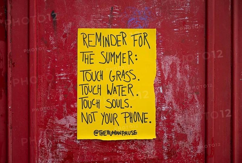 Yellow poster on phone box reminds people to appreciate nature and put their mobile phones away, Kensington, London, England, United Kingdom