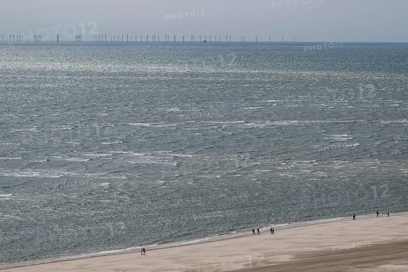 Wide sea view with sandy beach and pedestrians, wind turbines on the horizon, North Sea, Denmark