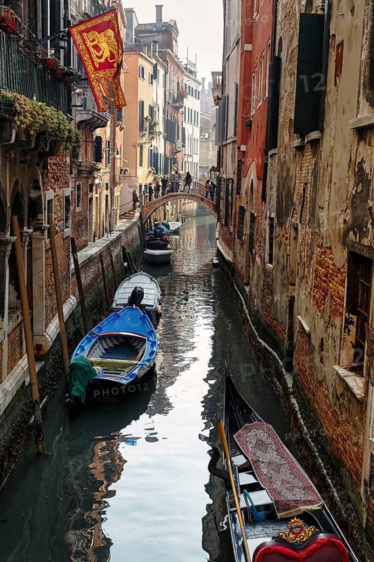 Strollers on a small bridge, boats on a canal, typical street scene in Venice, Italy