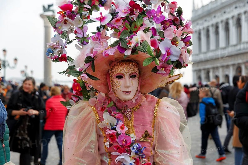 Venetian mask, disguised woman with big hat, walker, crowd on St Mark's Square, Carnival in Venice, Italy