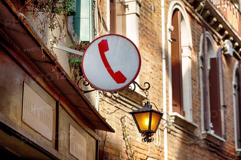 Sign with pictogram, red telephone receiver, public telephone, facade of a restaurant with street lamp, nostalgia, Venice, Italy