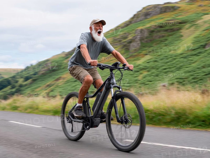 A senior citizen rides a mountain bike, e-bike, pedelec on a sloping road in a rural area, motion blur, AI generated, AI generated