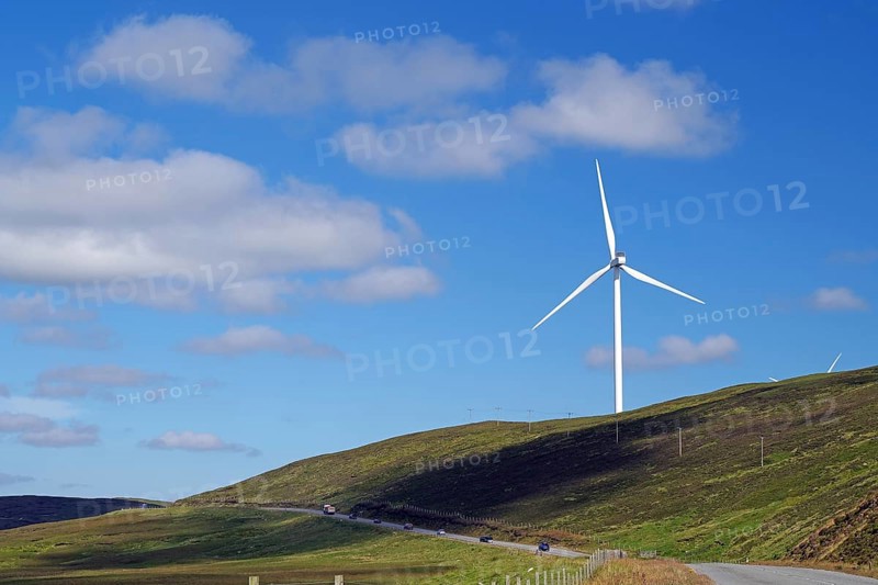 Single wind turbine on a hill next to a road under a blue sky, Mainland, Shetland Islands, Scotland, United Kingdom