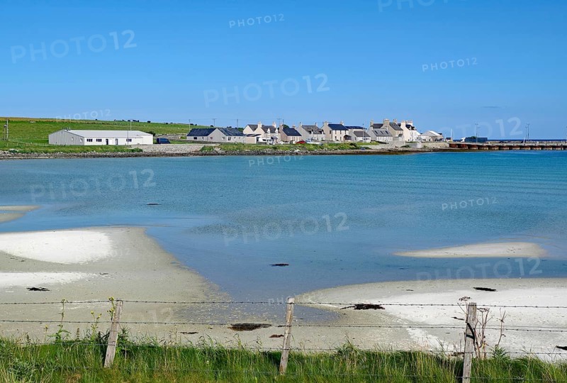 Coastline with sand and village by the shimmering blue sea, Pierowal, Westray, Orkney Islands, Scotland, Great Britain
