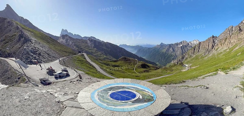 Panoramic view to the left small car park of Col Agnel Colle dell' Agnello dell'Agnello in the background southern ramp of Alpine pass above tree line with border marking of national border national border between France Italy on highest border pass third highest asphalted pass in the Alps mountain road Alpine road border course, front centre orientation board at viewpoint, Molines-en-Queyras, Département Hautes-Alpes, Provence-Alpes-Côte d'Azur, France, Pontechianale, Piemont, Italy