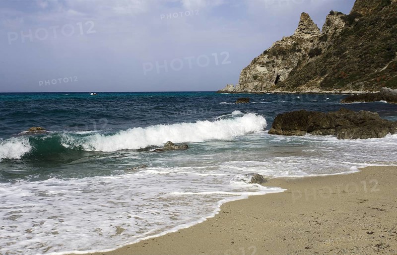 Waves rolling over the sandy beach, rocky coast in the distance, Ricadi, Capo Vaticano