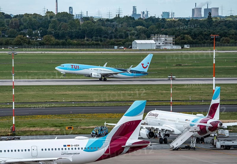Düsseldorf Airport, Eurowings Airbus aircraft on the apron, TUI Boeing 737-800 taking off, in the background the HKM steelworks in Duisburg, North Rhine-Westphalia, Germany