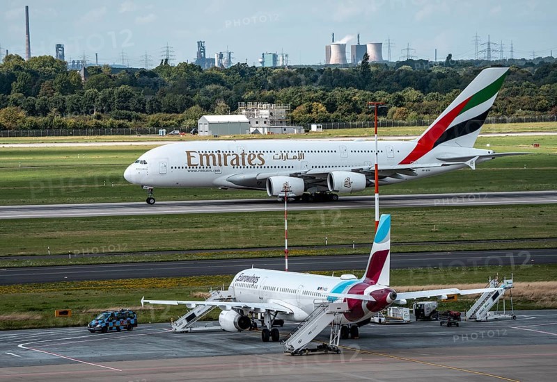 Düsseldorf Airport, Eurowings Airbus aircraft on the apron, Emirates Airbus A380-800 taking off, in the background the HKM steelworks in Duisburg, North Rhine-Westphalia, Germany