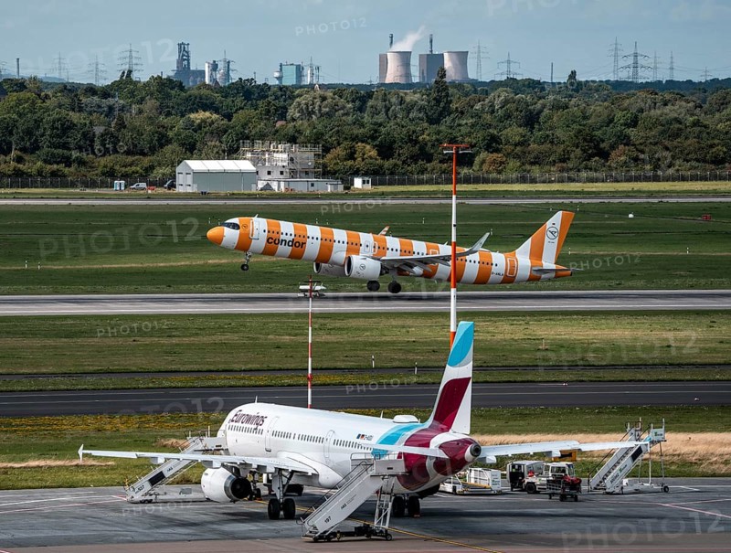 Düsseldorf Airport, Eurowings Airbus aircraft on the apron, Condor Airbus A321-200 taking off, in the background the HKM steelworks in Duisburg, North Rhine-Westphalia, Germany
