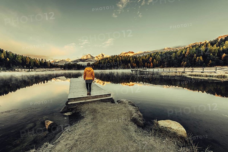 Young woman at Lake Staz near Sankt Moritz in the Engadine in Switzerland. Morning atmosphere with fog in autumn. Reflection of water