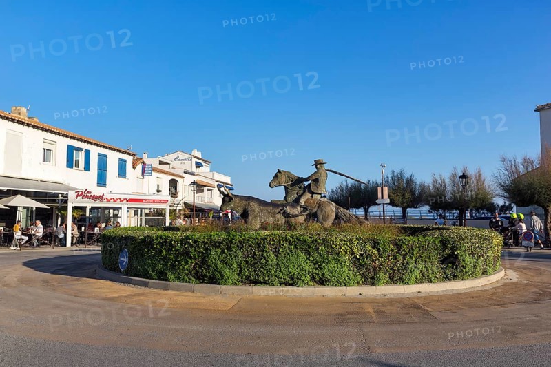Roundabout with sculptures, cattle herder, guardian of the Camargue on a horse, next to a bull, Saintes-Maries-de-la-Mer, Camargue, France
