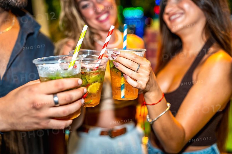 Friends enjoying refreshing cocktails together at a lively summer party, celebrating and having a good time