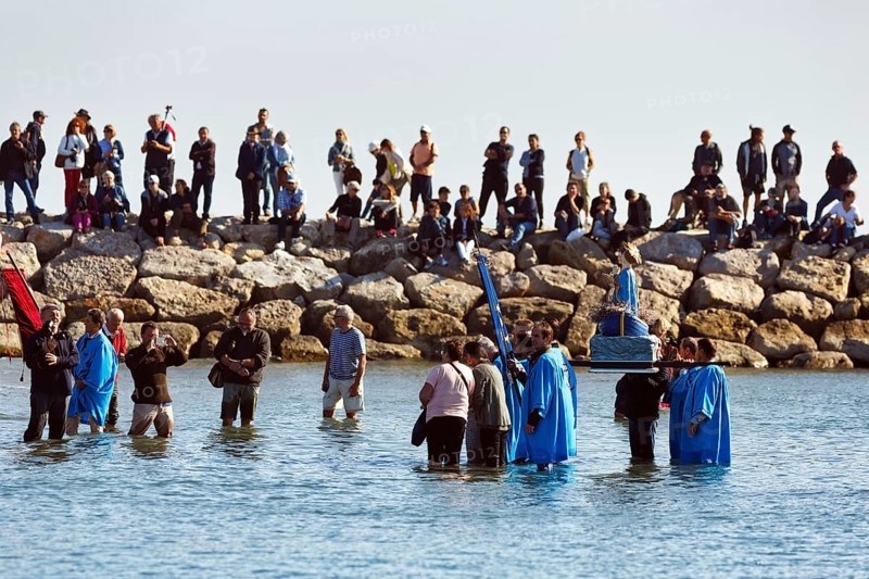 Crowd during pilgrimage, procession by the sea, pilgrims walking through water, statue of the Virgin Mary, Saintes-Maries-de-la-Mer, Camargue, France