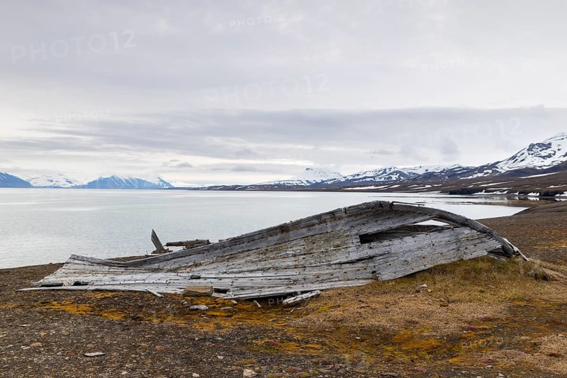 Broken wooden boat on the beach, mountain range, snow, sea, arctic spring, Bamsebu, Spitsbergen, Svalbard