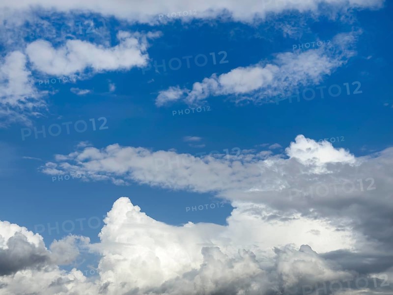 Below white cumulus clouds, centre above stratocumulus above altostratus in front of blue sky, International