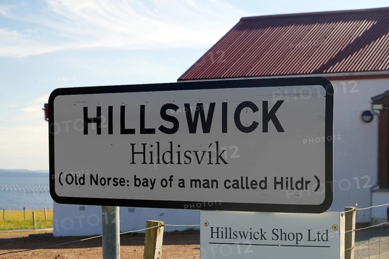 Hillswick town sign in front of a building with historical reference to Old Norse names, Eshaness, Shetland Islands, Scotland, United Kingdom