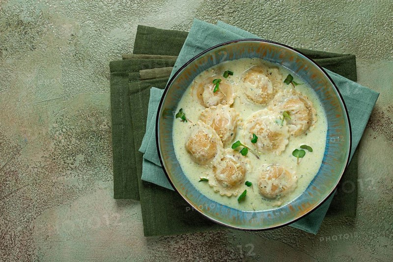 Ravioli in cream sauce, spices and herbs, top view, no people