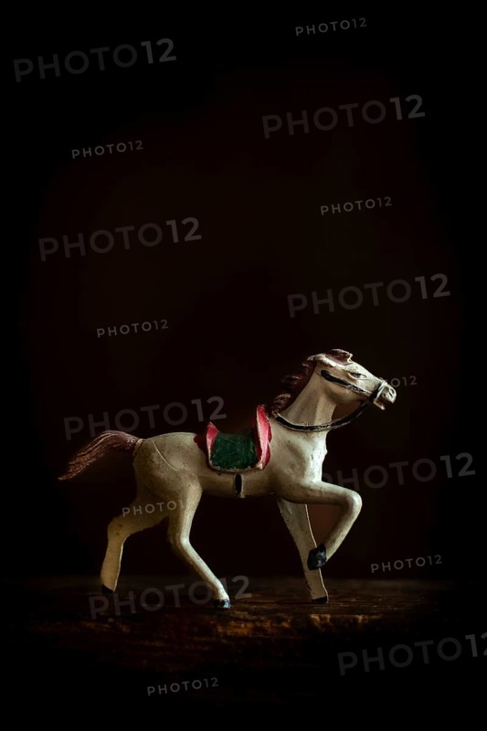 A vintage toy horse trots gracefully across a soft, warm background, highlighting its intricate craftsmanship and evoking a sense of nostalgia and charm