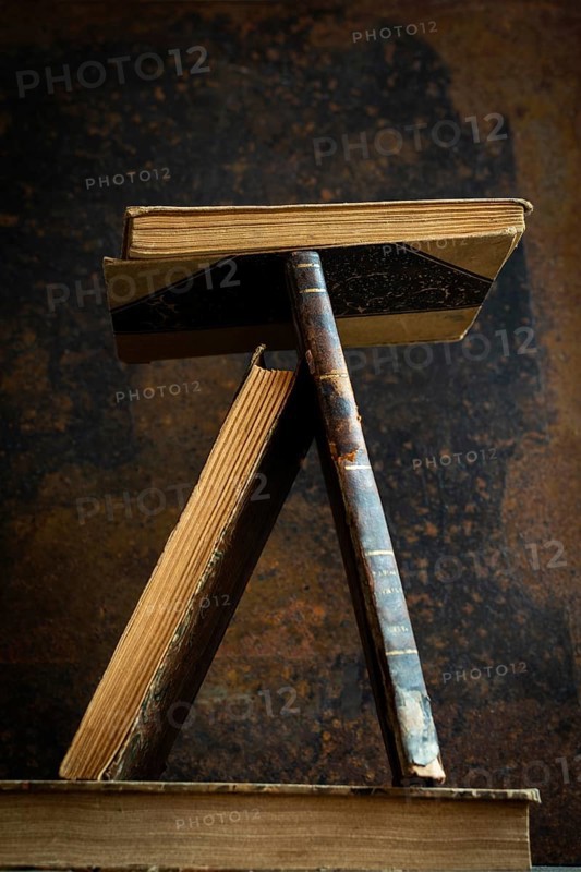 A vintage book stand showcases several old books in a unique position, highlighting their worn textures against a rich, textured background that tells a story